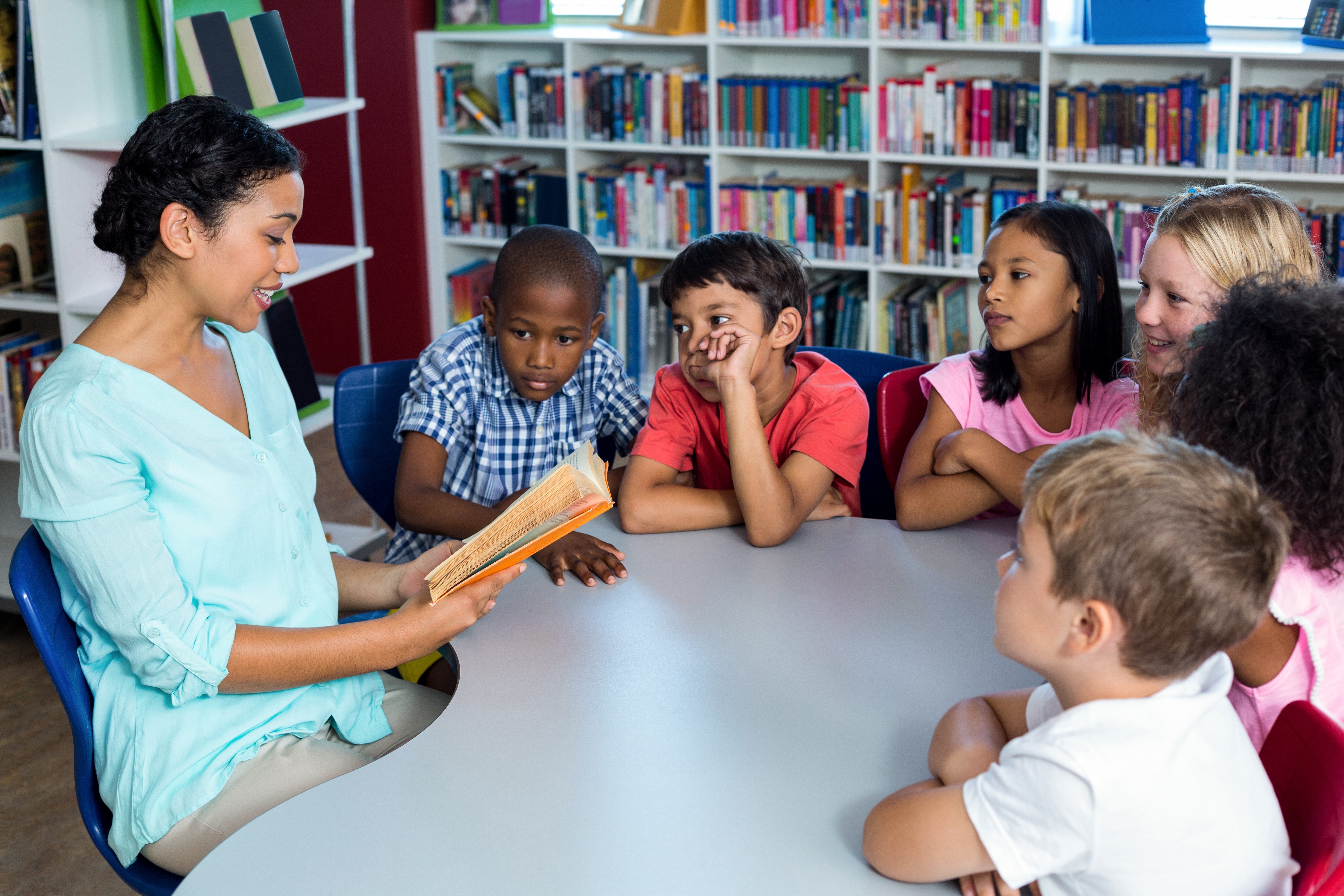 Teacher reading a book to mixed race children